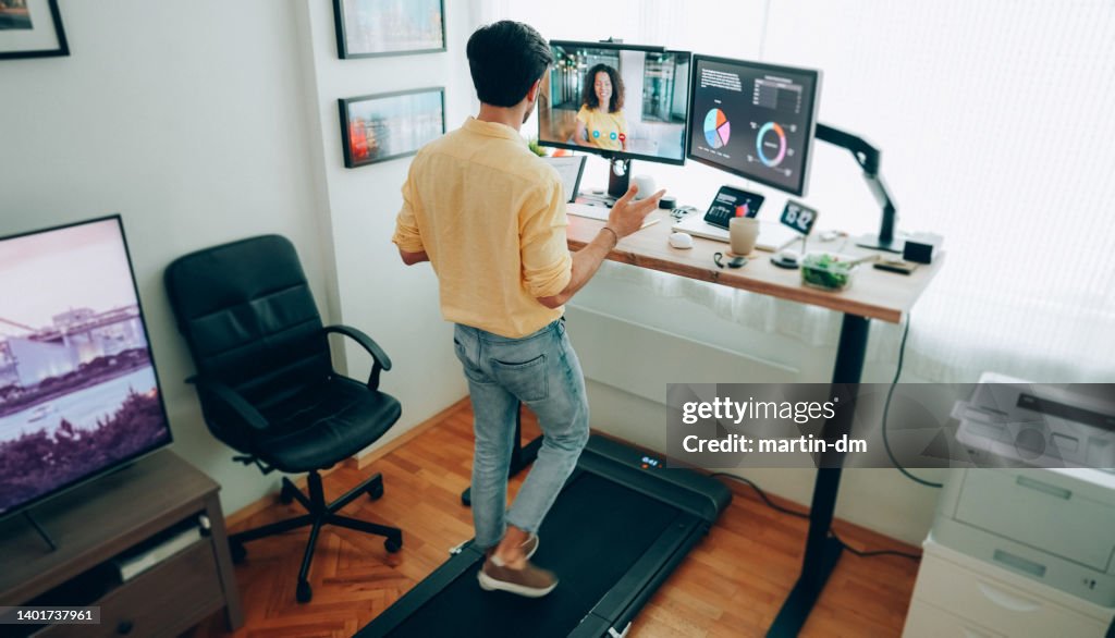 Man at standing desk home office talking on business video call