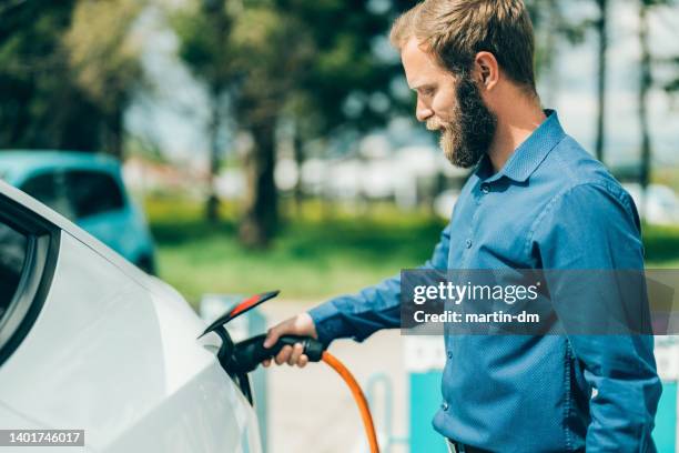 mann elektroauto aufladen - elektro auto stock-fotos und bilder