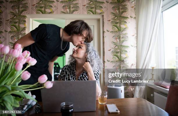 teenage son kissing his mother on the head - affectionate stock photos et images de collection