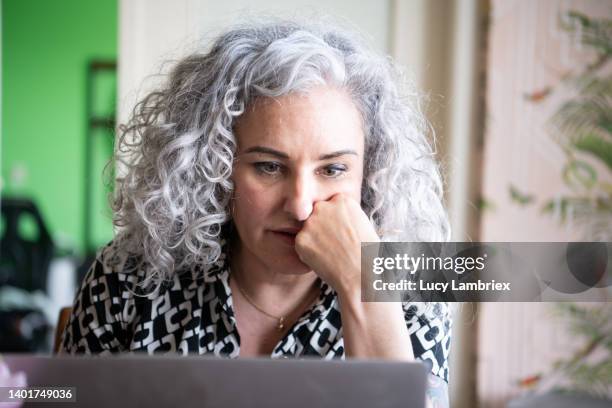 beautiful gray-haired woman working at home - vrouw behangen stockfoto's en -beelden