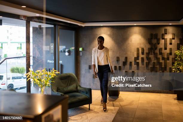 wide shot businesswoman enters luxury hotel lobby - businesswoman hotel stock pictures, royalty-free photos & images