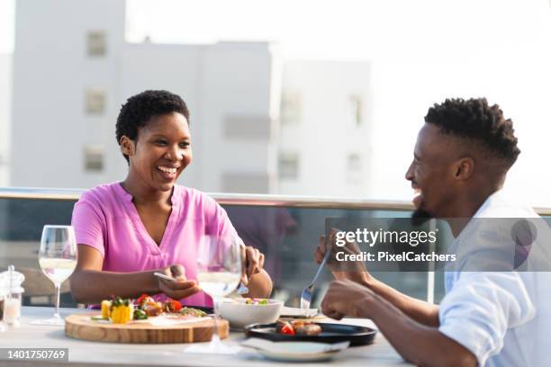 coppia che ride insieme gustando il pranzo in un bar sul tetto - rooftop dining foto e immagini stock