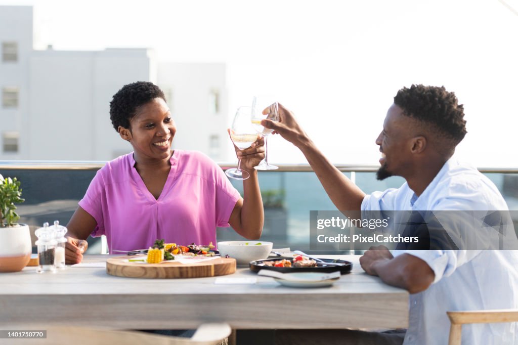 Couple raise glasses celebrating the good life enjoying lunch together at a rooftop cafe