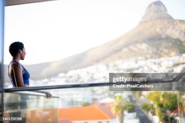 wide shot woman in yoga clothes on balcony enjoying view over city early morning - african cityscape stockfoto's en -beelden