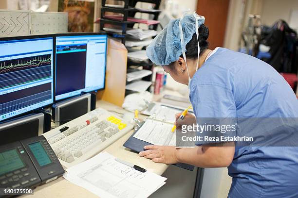 nurse prepares surgical paperwork - medisch dossier stockfoto's en -beelden