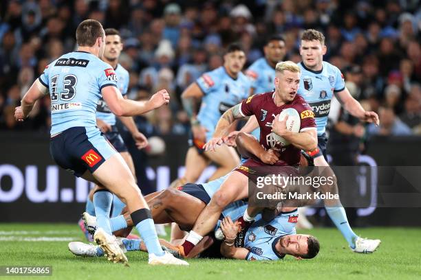Cameron Munster of the Maroons is tackled during game one of the 2022 State of Origin series between the New South Wales Blues and the Queensland...