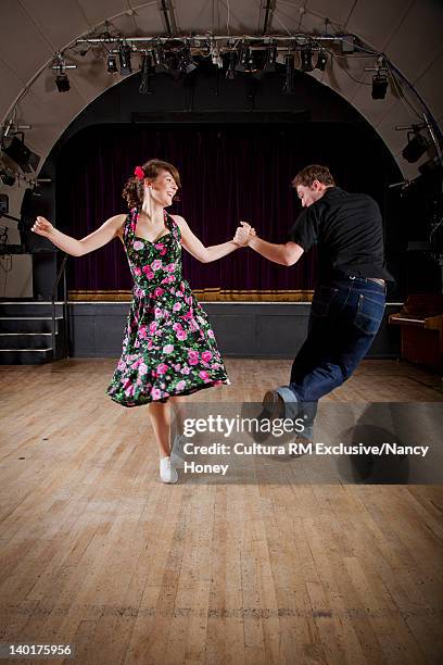 smiling couple dancing in auditorium - swing dance stock pictures, royalty-free photos & images