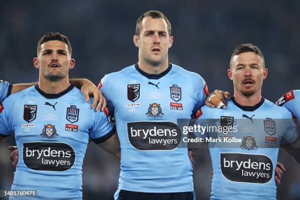 Nathan Cleary, Isaah Yeo and Damien Cook of the Blues stand for the national anthem before game one of the 2022 State of Origin series between the...