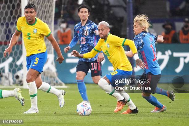 Neymar Jr. Of Brazil in action under pressure from Junya Ito of Japan during the international friendly match between Japan and Brazil at National...