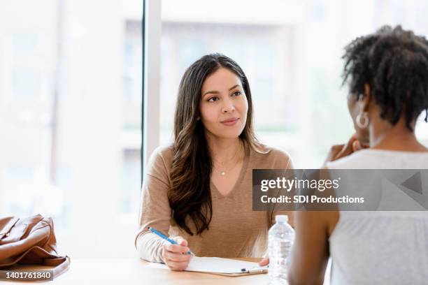 mid adult female therapist listens to unrecognizable female client - employee review stock pictures, royalty-free photos & images