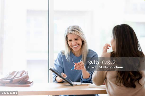 female financial advisor reviews documents on digital tablet - consulting business stockfoto's en -beelden