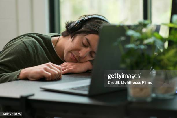 exhausted worker falls asleep at his desk inside an office - perder el tiempo fotografías e imágenes de stock