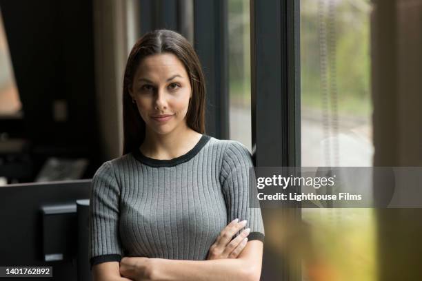 portrait of confident businesswoman next to office window - sonrisa satisfecha fotografías e imágenes de stock