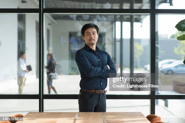 portrait of asian businessman standing in board room - asian businessman serious stock pictures, royalty-free photos & images