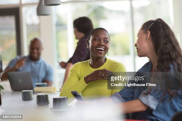 two friends chat together at a coffee shop counter - coffee shop chat stock-fotos und bilder