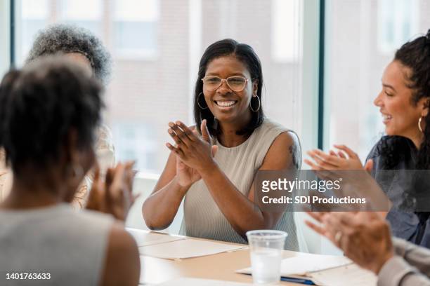 grupo de empleados sonríe y aplaude tras un año exitoso - women in business group fotografías e imágenes de stock