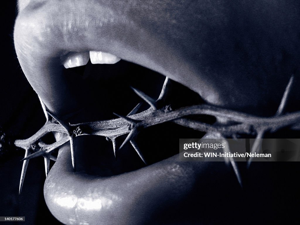 Close-up of a man's mouth with thorns