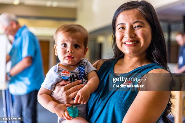 filipino woman and her baby boy after voting in an american election - polling place stock pictures, royalty-free photos & images