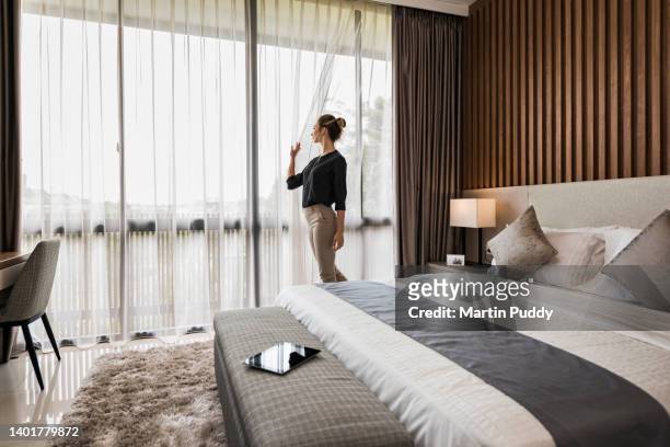 young caucasian woman at home, looking out of  modern bedroom window - bored housewife 個照片及圖片檔