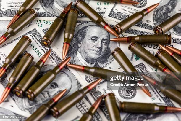 hundred dollar bills and machine gun cartridges. concept of economic crisis due to war - money penalty stock pictures, royalty-free photos & images