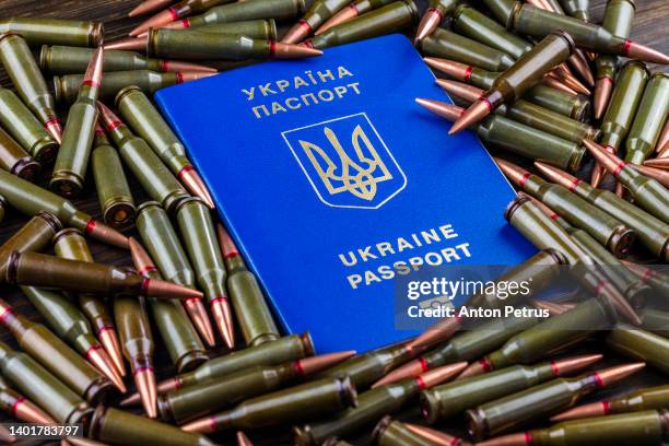 ukrainian passport on the background of machine gun cartridges. war in ukraine - ukrainian culture stock pictures, royalty-free photos & images