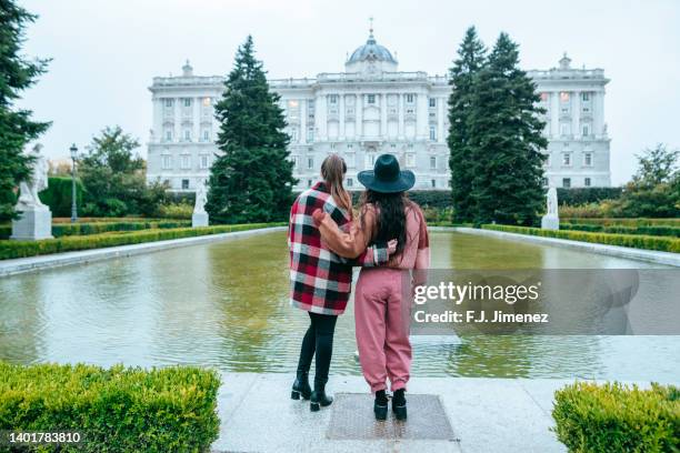 two women in park looking towards the royal palace of madrid - palacio real de madrid fotografías e imágenes de stock