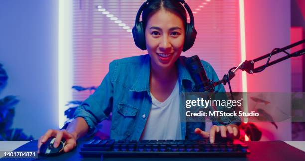 young asian woman playing online computer video game and broadcast streaming live in neon lights living room at home. - live streaming stock pictures, royalty-free photos & images