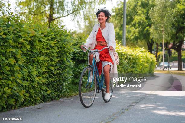 bella latina in sella a una bicicletta - adulto di mezza età foto e immagini stock