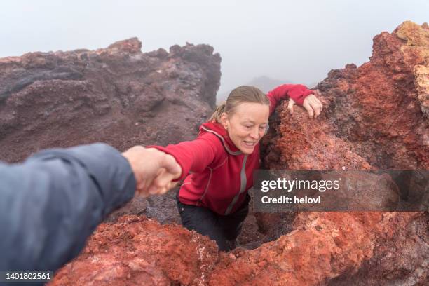 mano tirando de las mujeres por la roca volcánica - erupción del volcán eldfell, islas westman - heimaey fotografías e imágenes de stock