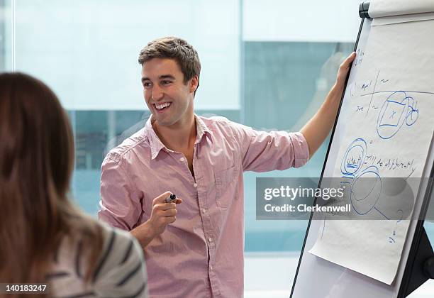 smiling businessman at flipchart - flipchart stock pictures, royalty-free photos & images