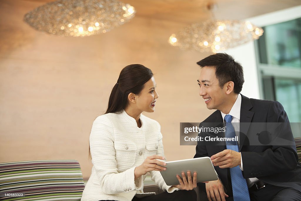 Businessman and businesswoman using digital tablet in meeting