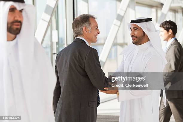 businessman in suit shaking hands with businessman in kaffiyeh - western europe stock pictures, royalty-free photos & images