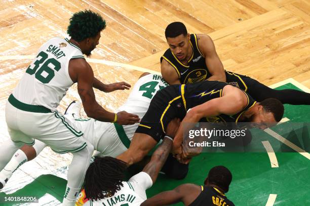 Stephen Curry and Jordan Poole of the Golden State Warriors compete for a loose ball against Al Horford of the Boston Celtics in the fourth quarter...