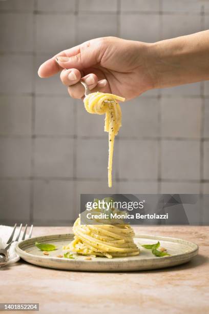 linguine pasta on plate with pesto and basil human hand - tenedor fotografías e imágenes de stock