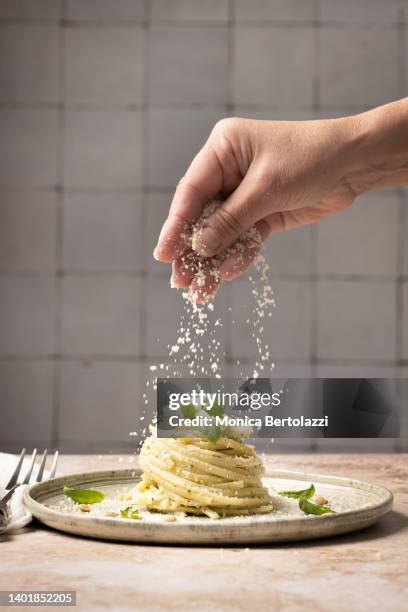 linguine pasta on plate with pesto and basil human hand - parmesan fotografías e imágenes de stock