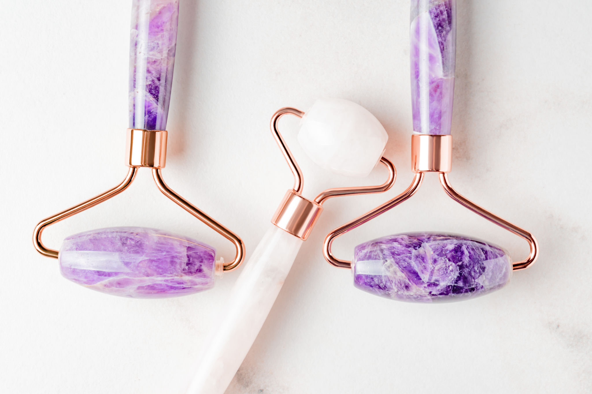 Face roller guasha massagers. Face skin care and anti age products. Chinese Gua Sha massage tools from rose quartz and ametyst. Close up, top view Face roller guasha massagers. Face skin care and anti age products. Chinese Gua Sha massage tools from rose quartz and ametyst. Close up, top view