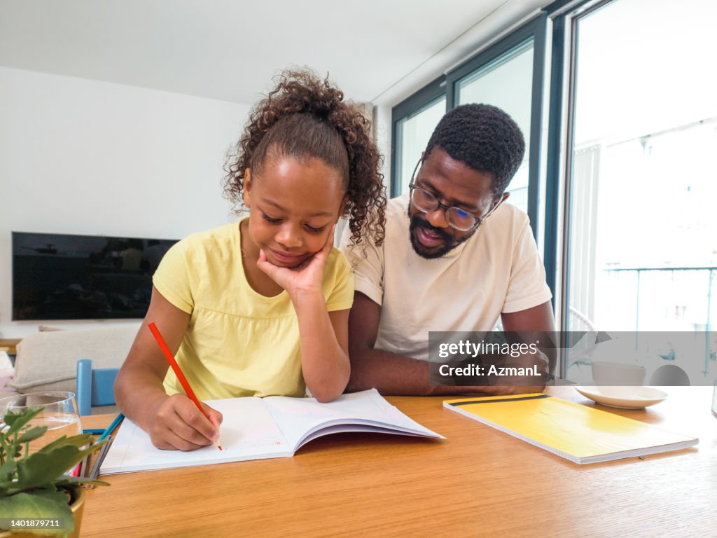 Mixed-Race Cute Girl Doing Homework with Happy Father At Home