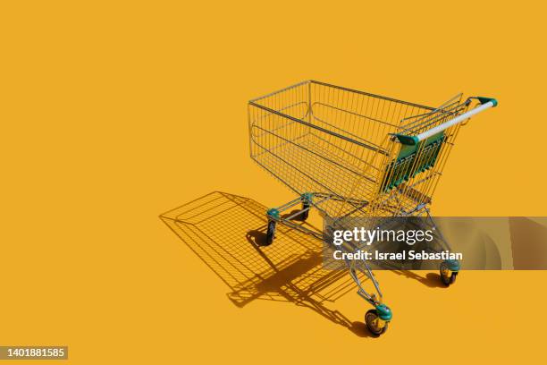 view of an empty shopping cart on an isolated yellow background. - shopping cart stock-fotos und bilder