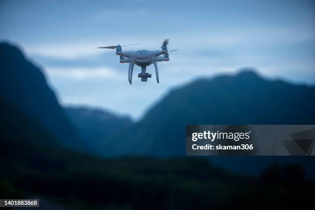 agricultural drone flying over the trees plantation with a mountain background - 無人操縦機 ストックフォトと画像