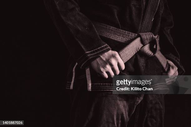 asian man practicing brazilian jujutsu- closeup of hand holding belt - dojo photos et images de collection