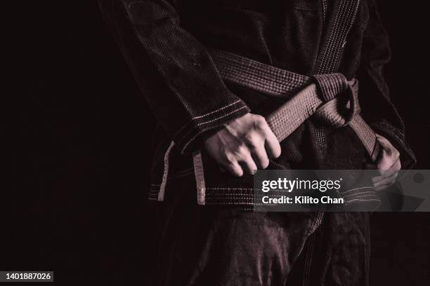 asian man practicing brazilian jujutsu- closeup of hand holding belt - jujitsu stock pictures, royalty-free photos & images