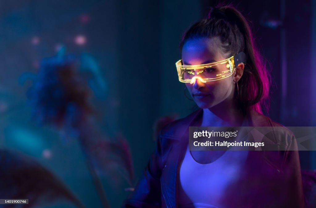 Futuristic young woman in VR environment with smart glasses.