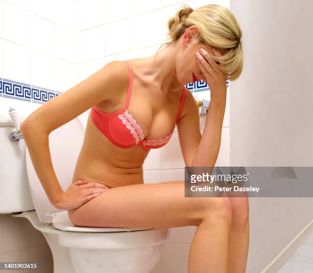 woman sitting on toilet with head in hands - woman hemorrhoids stock pictures, royalty-free photos & images