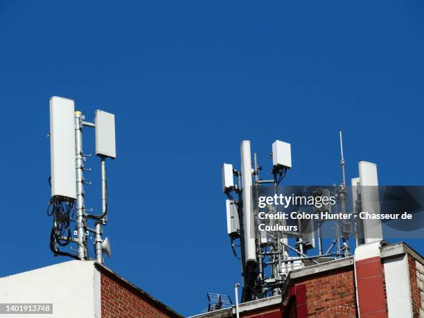 antennas for mobile telephony on the roof of a residential building and blue sky in paris, france - telecom tower stock pictures, royalty-free photos & images