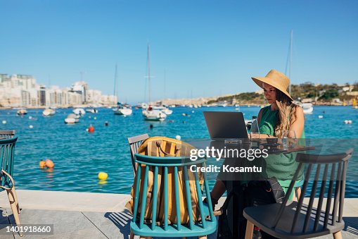 A business woman sitting in a coffee shop on the dock, not far from the sea and working on a laptop A business woman sitting in a coffee shop on the dock, not far from the sea and working on a laptop
