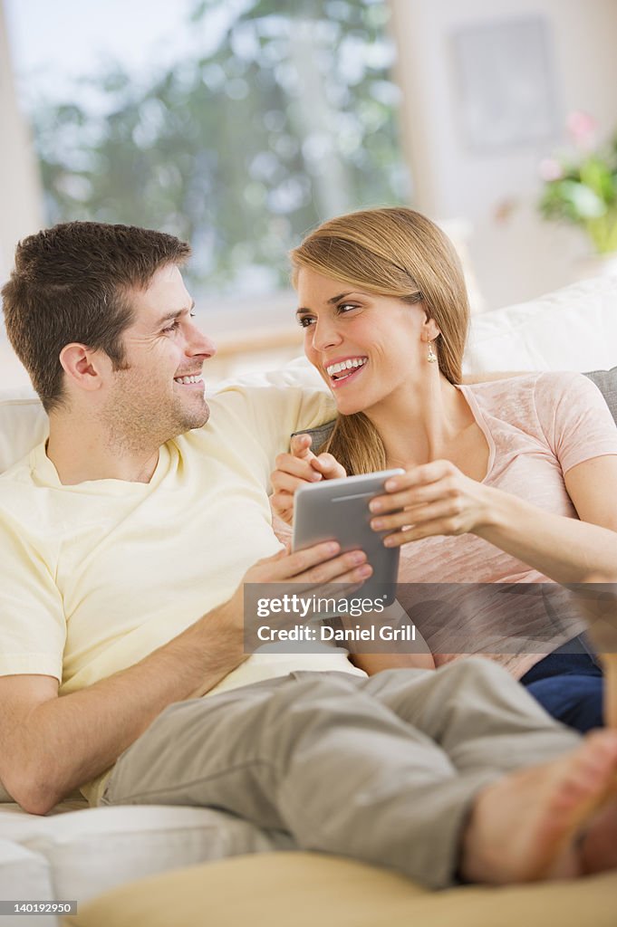 USA, New Jersey, Jersey City, Young couple sitting on sofa with digital tablet
