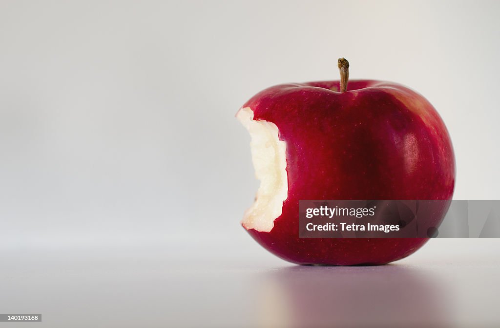 Red apple with missing bite, studio shot