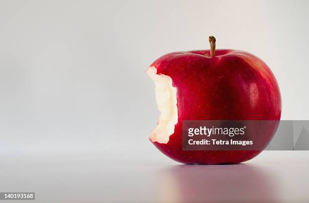 red apple with missing bite, studio shot - apple bite out stock pictures, royalty-free photos & images