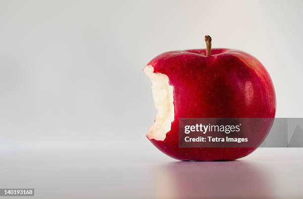 red apple with missing bite, studio shot - apple with bite stock pictures, royalty-free photos & images