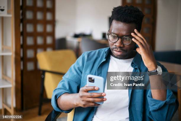 reading about bad news using a smart phone - african american man depressed bildbanksfoton och bilder